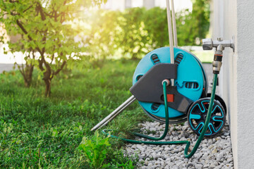 Hose Reel for Watering Garden. Garden Hose Cart and Hose Connector with Tap on Wall on Green...