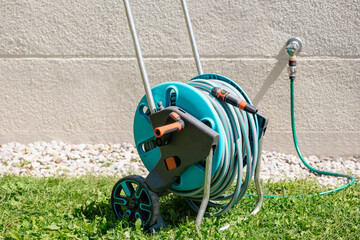 Naklejka premium Garden Hose Reel Cart Connected with Water Tap Outdoor Wall for Watering Lawn. 