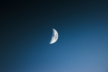 View of a serene half moon in a dark night sky with tranquil twilight atmosphere, Brulisau, Appenzell, Switzerland.