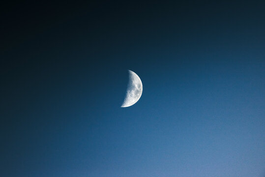 View of a serene half moon in a dark night sky with tranquil twilight atmosphere, Brulisau, Appenzell, Switzerland.
