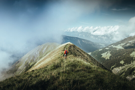 View of serene mountain landscape with a hiker amidst clouds and grass, Flums, St. Gallen, Switzerland.