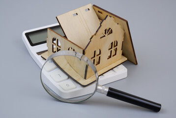 Destroyed house on calculator under magnifying glass on gray background. Check price for house...