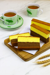 Lapis Surabaya or Indonesian layered sponge cake on wooden chopping board with cups of tea. White...