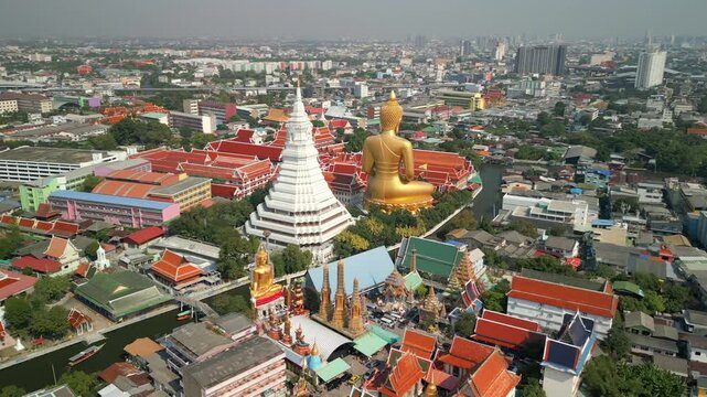 Aerial view of the Giant Golden Buddha at Wat Paknam Phasi Charoen with Bangkok skyline, showcasing Thailand's religious and cultural heritage