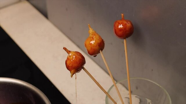 Coconut balls on wooden skewers during the preparation process of Brazilian dessert bala baiana.