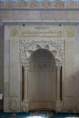 Beautiful arch in a spacious hall with Arabic hieroglyphs in a mosque close-up