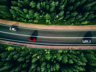 Aerial top view of highway asphalt road with cars driving and green summer woods