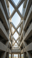 Obraz premium A symmetrical concrete corridor with repeating geometric patterns and open views.