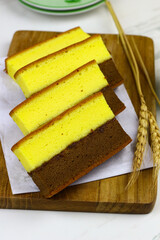 Lapis Surabaya or Indonesian layered sponge cake on wooden chopping board with cups of tea. White marble background.