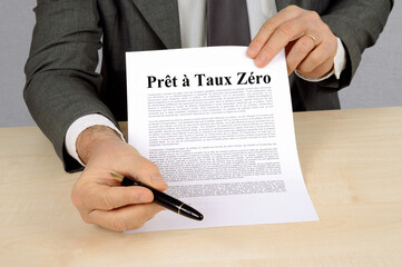 Homme tenant un contrat de prêt à taux zéro et donnant un stylo pour la signature