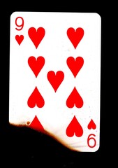 A partly burnt playing card in the suit of hearts.