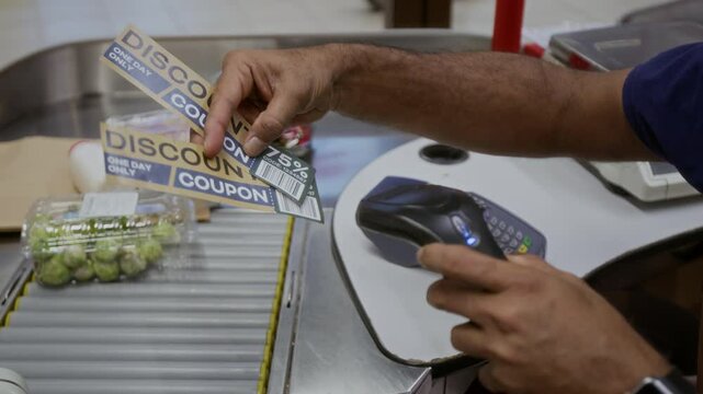 Closeup of unrecognizable male cashier scanning discount coupons in supermarket with focus on hands holding scanner