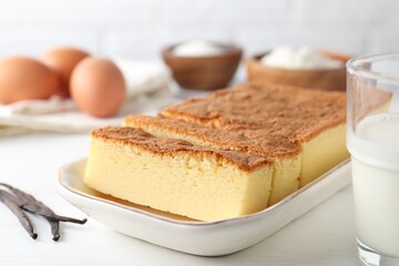 Tasty Japanese Castella sponge cake and ingredients on white table, closeup