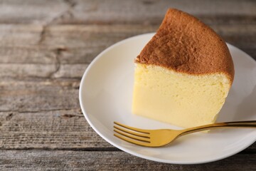 Piece of tasty Japanese Castella sponge cake and fork on wooden table, closeup. Space for text