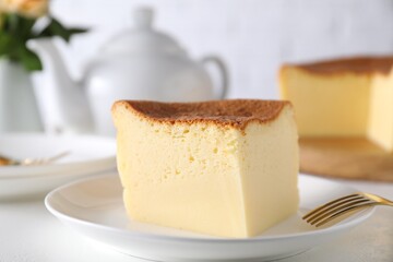 Piece of tasty Japanese Castella sponge cake and fork on white table, closeup
