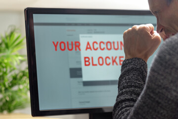 Worried young man having problems with blocked bank account. Capturing a moment of frustration, a man faces a frozen screen while managing accounts, highlighting the importance of tech solutions