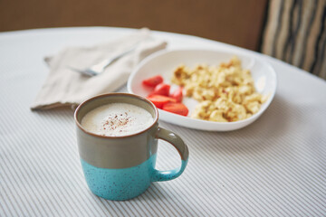 Breakfast table. Cup of coffee and plate with scrambled eggs and vegetables on the table