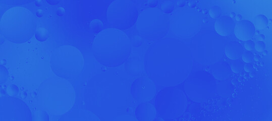 Bright blue background with abstract oil bubbles in liquid. Macrophotography creates an effect of texture and depth. Perfect for backgrounds, design and scientific concepts.