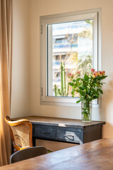 Sunny home office corner with vintage desk, flowers and window view