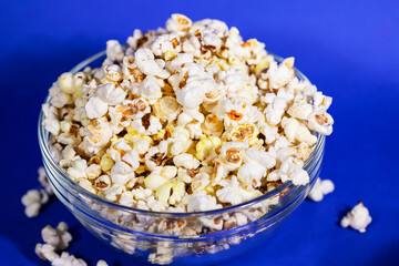 Bowl full of healthy butter popcorn on blue background