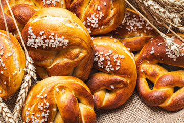 Pretzels with coarse salt. on canvas in a wicker basket with ears of wheat.