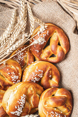 Pretzels with coarse salt. on canvas in a wicker basket with ears of wheat.