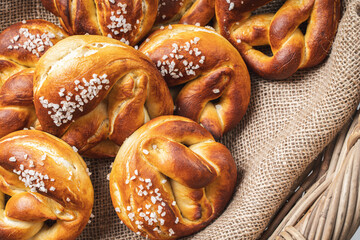 Pretzels with coarse salt. on canvas in a wicker basket with ears of wheat.