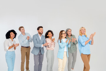 Fototapeta premium Group of diverse business professionals clapping together in a collaborative and friendly environment on a neutral grey background.