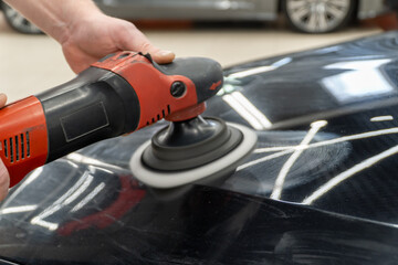 Car detailing series: Polishing black car close-up. The process of polishing the car body in...