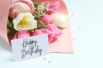 Beautiful bouquet of flowers with Happy Birthday card on light background, close up