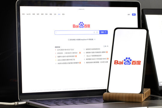 Baidu company logo and browser are seen displayed on a smartphone and on the computer screen in the background. Baidu, Inc. is a Chinese multinational technology company.
