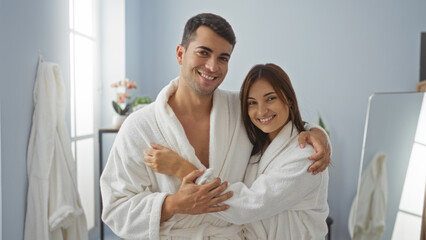 Obraz premium Smiling couple in bathrobes enjoying a relaxing day at a spa with bright airy wellness room