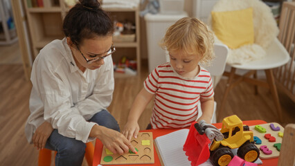 Mother and son play together in a cozy home bedroom, engaging with educational toys and a puzzle on the floor, showcasing family bond and teaching moments indoors.