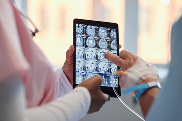 Two medical professionals analyzing detailed scans on a digital tablet, focused on diagnosing...