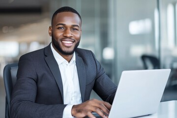 Fototapeta premium Man in a suit is sitting at a desk with a laptop in front of him