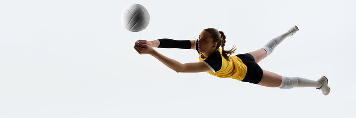 Young woman in yellow jersey and black shorts, volleyball player in motion, hitting ball isolated...