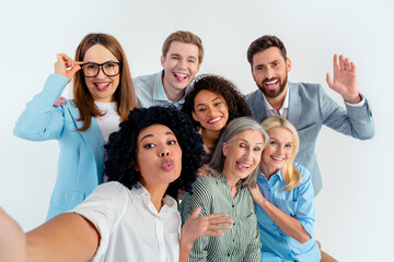 Obraz premium Cheerful group of coworkers posing for a playful selfie in a modern office setting with a diverse personality representation on a grey background.