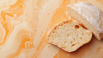 Cut loaf of crusty bread with white flour on an orange marble-like surface