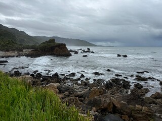 Expansive scenic coastline, clear day, mountains beaches and greenery in the foreground, New Zealand Pancake Rocks