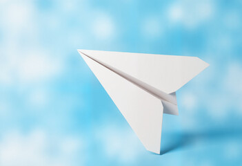 White paper airplane soaring in the air against a blue sky
