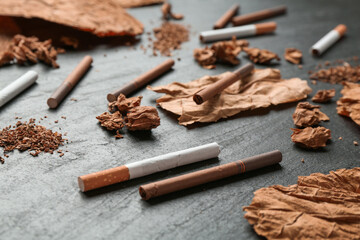 Tobacco, dried leaves and cigarettes on black table, closeup