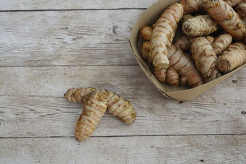 Fresh turmeric roots in cardboard box on rustic wooden table