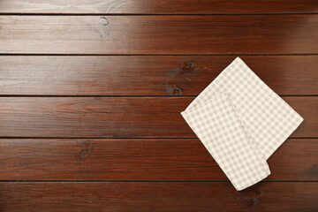 Checkered napkin on wooden table, top view. Space for text