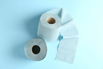 Color toilet paper rolls on light blue background, top view