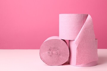 Color toilet paper rolls on pink background. Space for text