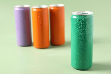 Colorful aluminium cans of beverage on pale green background