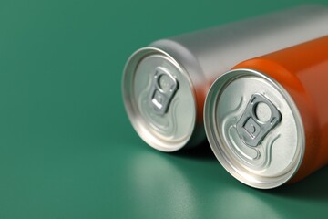 Two aluminium cans of beverage on green background, closeup. Space for text