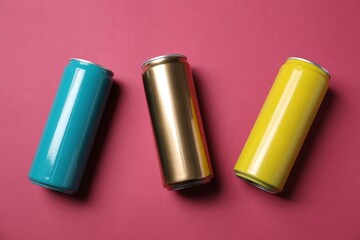 Three tin cans on pink background, flat lay
