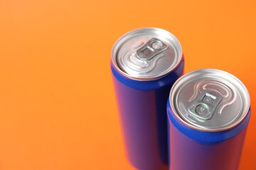 Two tin cans on orange background, closeup. Space for text