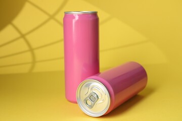 Two tin cans on yellow background with shadow